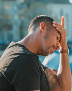 Mann mit Hand am Kopf wirkt nachdenklich und belastet durch Selbstzweifel.