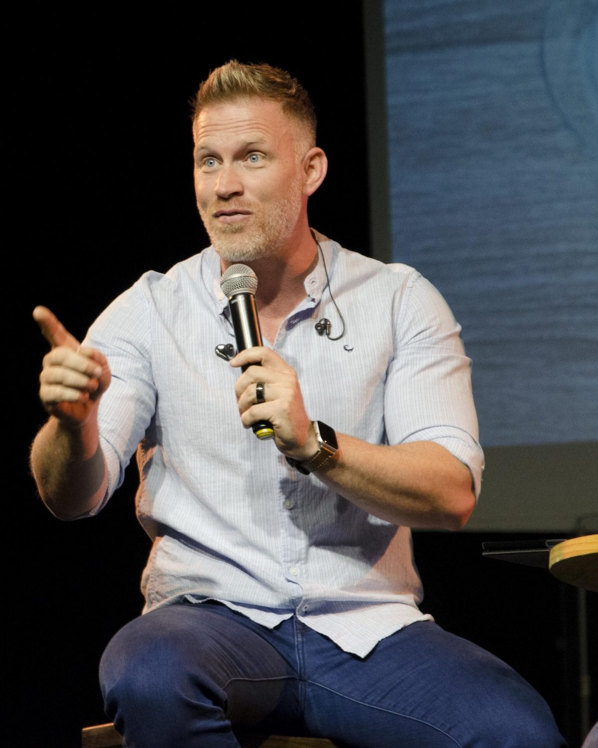 Coach spricht auf einer Bühne mit Mikrofon über Mindset-Themen.