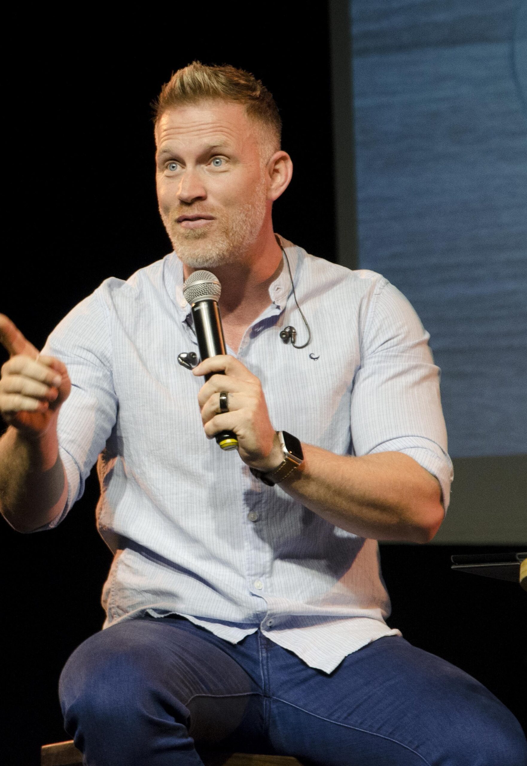 Coach spricht auf einer Bühne mit Mikrofon über Mindset-Themen.